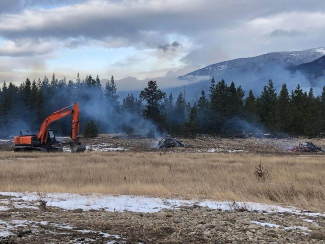 A photo taken by Natalie Dechka of Spaz Logging, showing removal and burning of wood debris from a marshland area in winter to enhance vegetation growth and improve shoreline access.